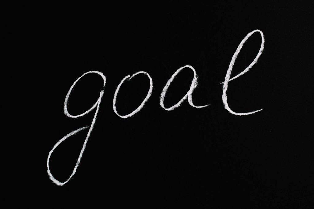 Elegant handwritten 'goal' on a black chalkboard background conveying ambition and purpose.